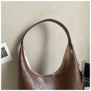 Détail du sac demi-lune en similicuir marron avec pendentif en perles de bois