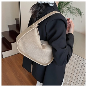 Sac hobo beige chic en aspect daim porté à l'épaule avec un blazer noir élégant