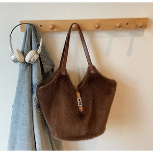 Detailed close-up of dark brown plush tote bag with leather strap and silver metal buckle