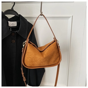 Détail du sac à bandoulière en daim marron avec boucles dorées et garniture en cuir