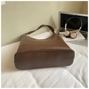 Gros plan d'un sac cabas marron foncé avec texture grainée et logo doré discret