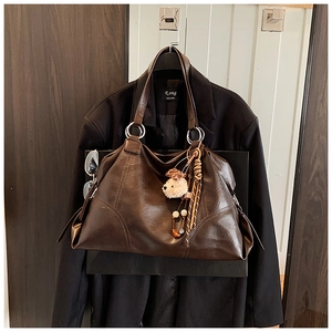 Dettaglio della borsa tote in pelle marrone scuro con anelli e ciondolo a forma di orso