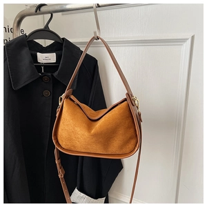 Détail du sac à bandoulière en daim marron avec finitions en cuir et boucles dorées