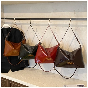 Dettaglio di quattro borse hobo vintage in vari colori appese a un supporto di metallo