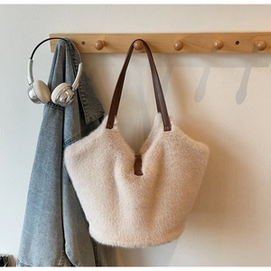 Detailed view of plush tote bag with faux fur texture and brown leather strap handles