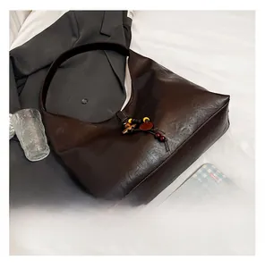 Detail of dark brown tote bag featuring retro matte texture and wooden bead charm