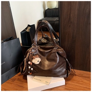 Dettaglio borsa tote marrone scuro in finta pelle con ciondolo a forma di animale bianco