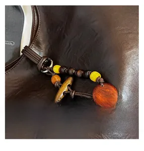 Close-up of dark brown leather tote with wooden beads and resin charm detail