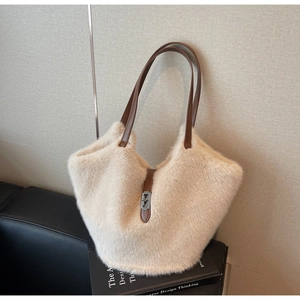 Detail view of large plush tote bag with brown leather handles and metal twist lock decoration
