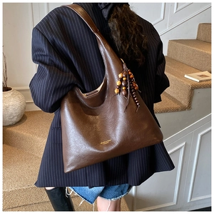 Détail du sac fourre-tout marron en similicuir avec lettrage doré et gland en perles de bois