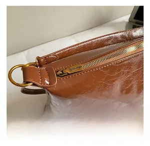 Dettaglio della cerniera in bronzo e pelle marrone lucida della borsa a tracolla