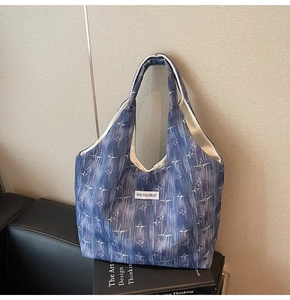 Detail of navy blue tote bag featuring white star patterns and Kiss Yourself label