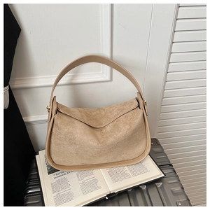 Détail du sac cabas en suédine beige avec bordure en cuir posé sur un magazine