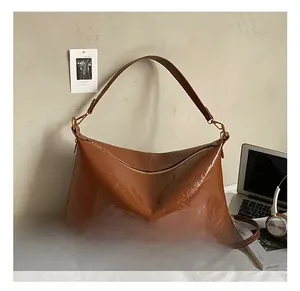 Dettaglio della borsa hobo in pelle verniciata marrone con tracolla larga e zip in metallo