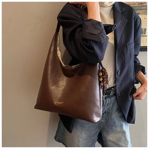 Détail d'un grand sac cabas marron avec gland en perles de bois et logo doré gravé
