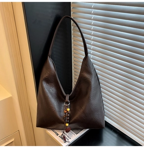 Detail of dark brown retro tote bag with wooden bead charm and textured PU leather