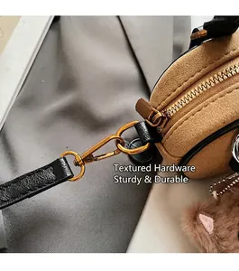 Close-up of retro gold hardware and plush charm on brown suede baguette bag details