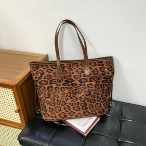 Detail of leopard print tote bag with brown faux leather trim and gold metal rings