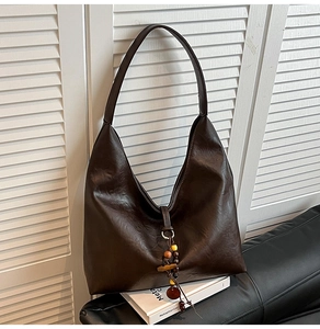 Detail of a dark brown Hobo shoulder bag with retro wood and colorful bead tassel pendant