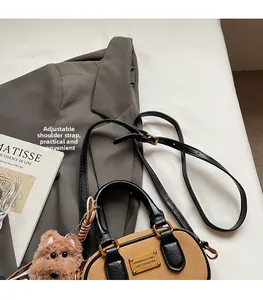 Dettaglio della borsa Boston vintage con placca dorata e ciondolo a forma di cucciolo