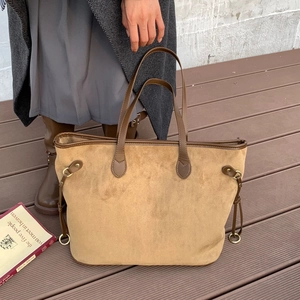 Detailed view of large brown suede tote bag with leather handles and side buckle straps