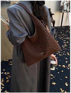 Détail d'un sac cabas léopard en daim avec perles vintage et logo de marque doré