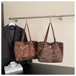 Detail of leopard print tote bags with cute bear embroidery hanging on a metal rack