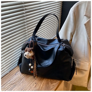 Dettaglio di una grande borsa tote in ecopelle nera con un ciondolo a forma di cagnolino