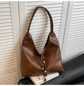 Detail of vintage brown PU leather hobo bag with ethnic style tassel and wooden beads