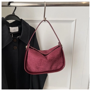 Détail du sac hobo bordeaux en daim et cuir lisse suspendu sur un crochet en métal