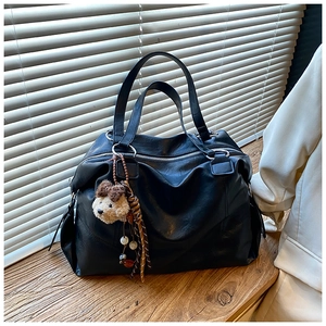 Dettaglio borsa shopper nera in pelle sintetica con ciondolo a forma di cagnolino