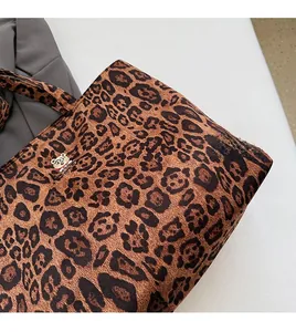 Detail of leopard print canvas tote bag featuring a cute bear patch and soft texture