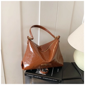 Dettaglio della borsa Hobo marrone lucida con placca in metallo e catena vintage