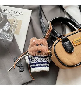 Detail of a brown plush bear keychain charm attached to a vintage boston style handbag