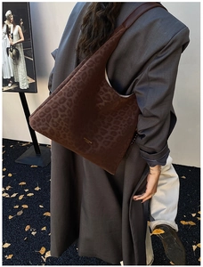 Détail du sac cabas en daim léopard marron foncé avec logo doré et texture veloutée
