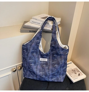 Close-up of star pattern canvas tote bag with kiss yourself tag on a black chair