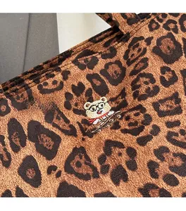 Close-up of leopard print tote bag with detailed cartoon bear embroidery and fabric texture