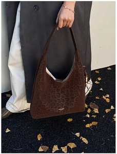 Détail d'un sac hobo léopard marron en daim avec logo doré pour un look automnal