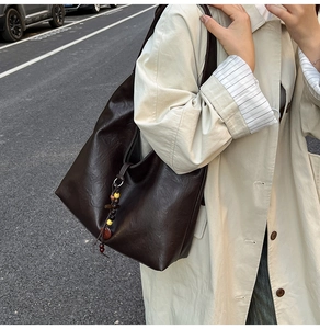 Detail of coffee brown PU leather tote bag with colorful wooden bead charm and thin strap