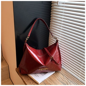 Dettaglio ravvicinato della borsa bordeaux in pelle lucida con hardware dorato elegante
