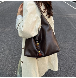 Detail of a large vintage brown leather tote bag with unique wood bead charm accessory