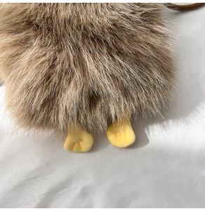 Detail shot of soft brown plush material and yellow feet of a cute cartoon crossbody bag