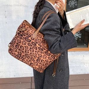 Detail of leopard print tote bag featuring brown leather handles and golden metal hardware