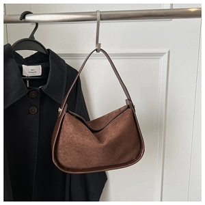 Détail du sac hobo en daim marron foncé avec boucle dorée et coutures lisses