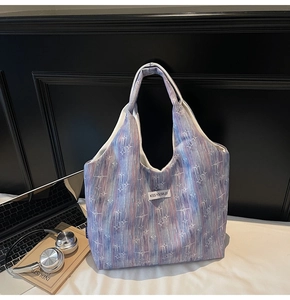 Detail view of tie-dye gradient tote bag with star patterns on white fabric surface