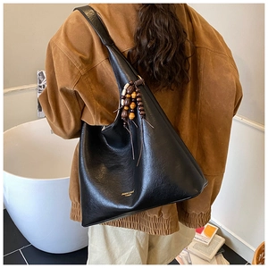 Détail du grand sac hobo noir avec gland en perles de bois et lettrage doré fin