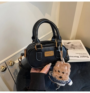 Dettaglio borsa Boston nera opaca con cerniera dorata e ciondolo orsetto di peluche