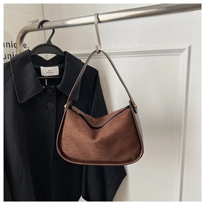 Vue détaillée du sac hobo en daim marron avec garniture en cuir suspendu sur crochet