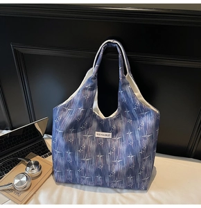 Detail of blue canvas tote bag with starburst print and white brand label on front