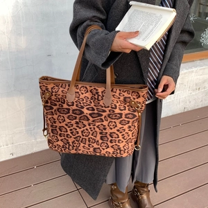 Close-up of leopard print tote bag with brown leather straps and metallic accents